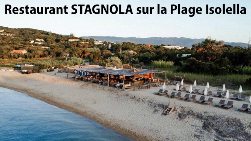 STAGNOLA-Vue aérienne du restaurant STAGNOLA sur la Plage Isolella, avec des transats sur le sable et des collines en arrière-plan.